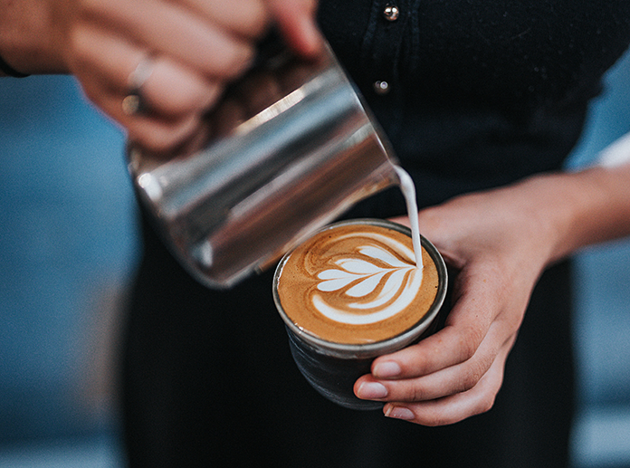 frau macht kaffee latte art